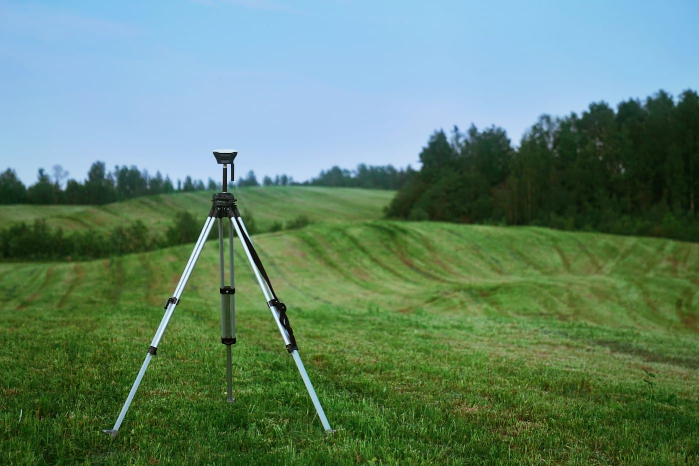 A survey tripod standing on an open green plot