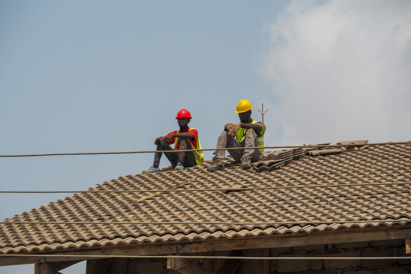 Two builders in hard hats on a tiled roof